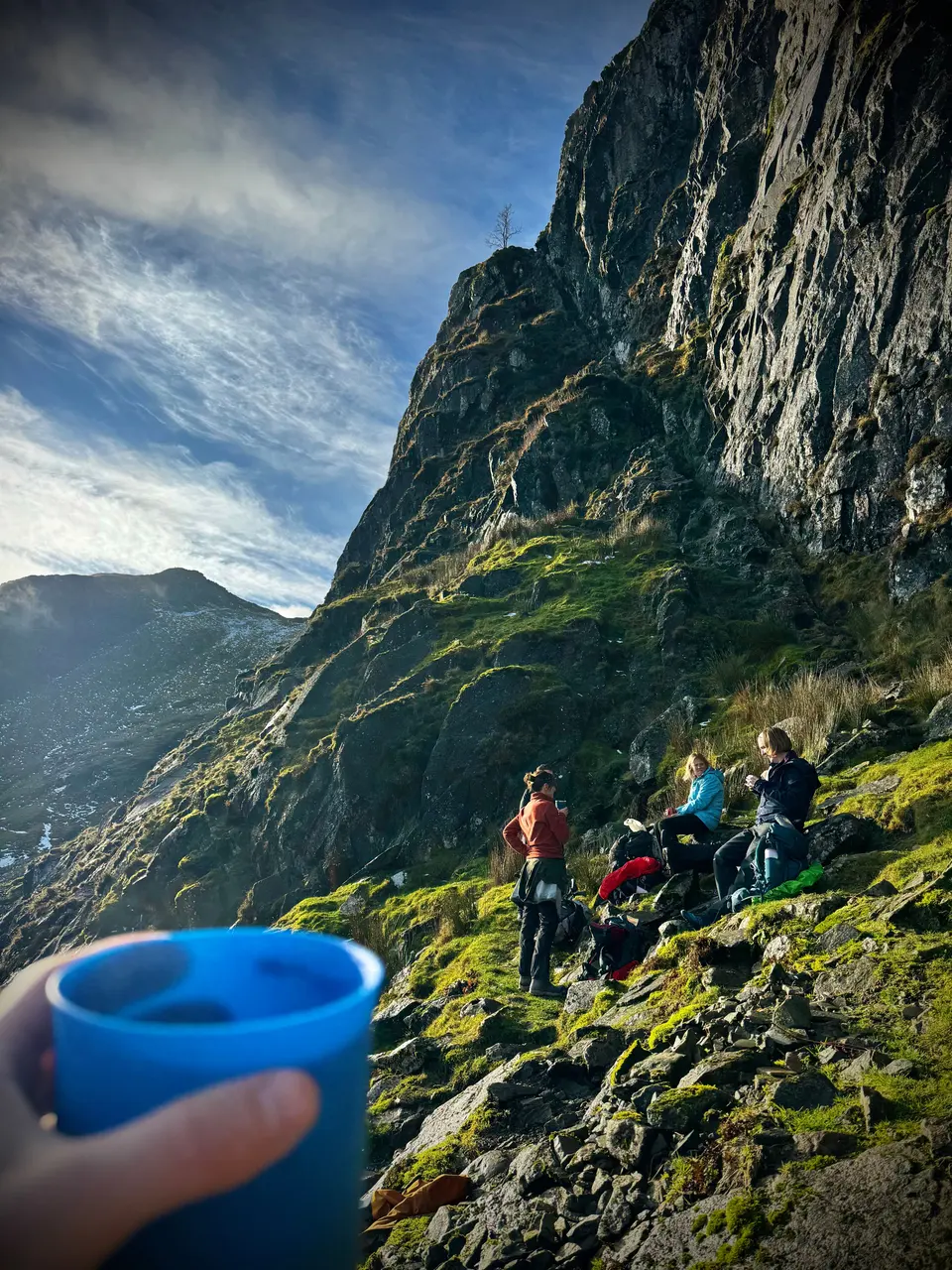 Walkers having tea below a crag