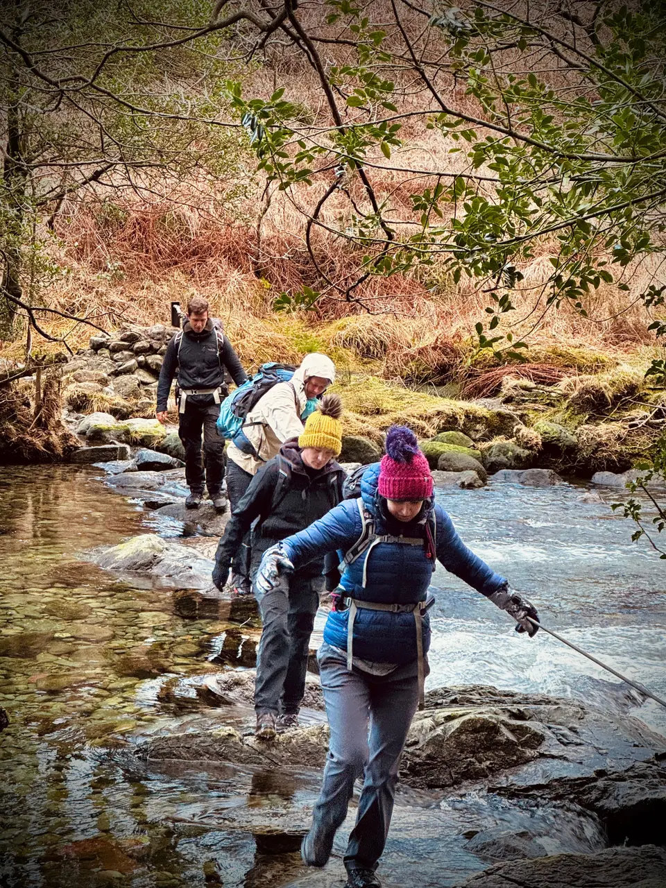 Hikers crossing stepping stones