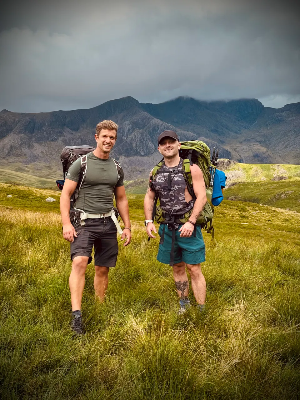 Tom and Dan carrying hiking packs in a mountain landscape