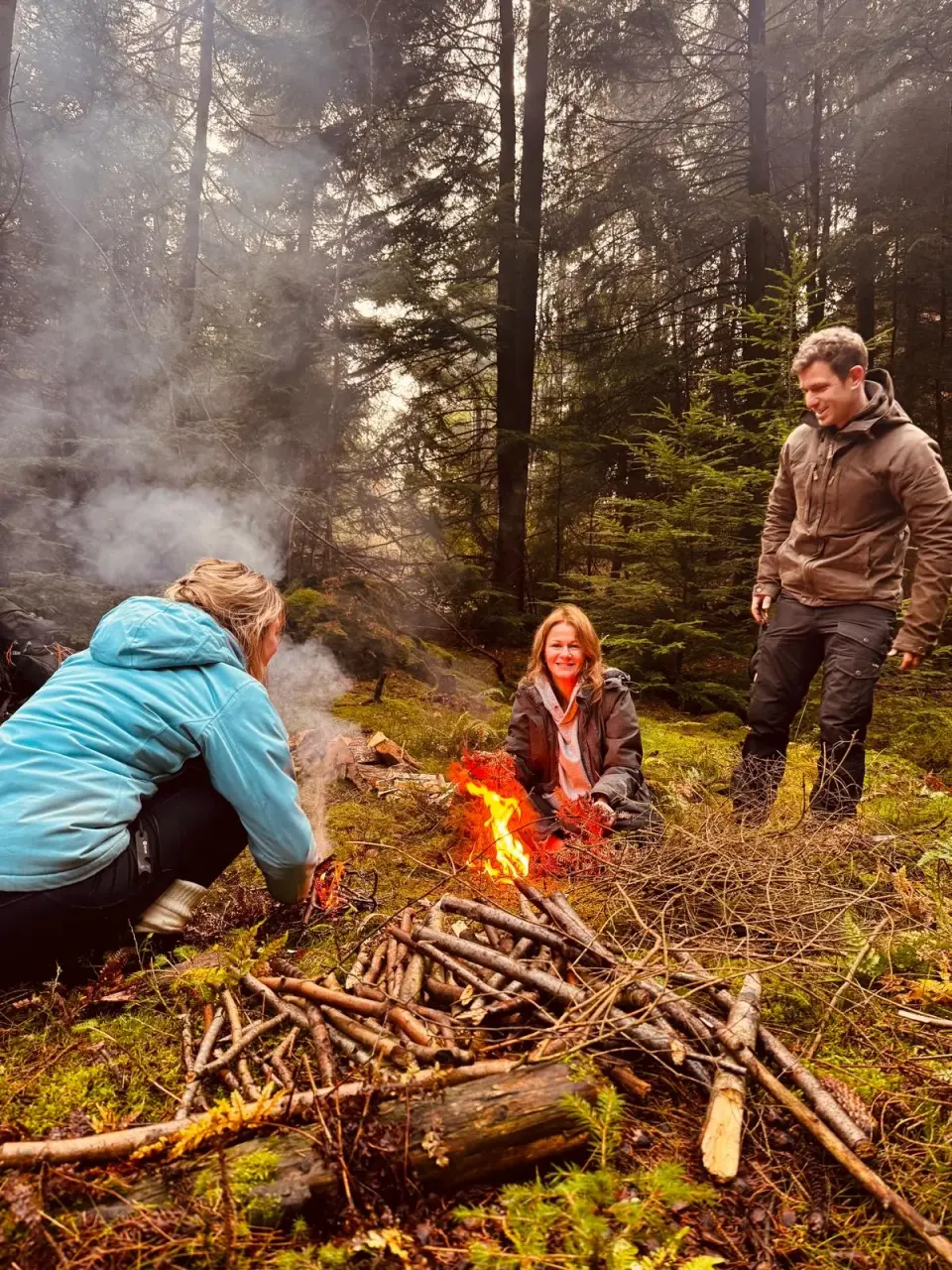 Colleagues around a fire in woodland